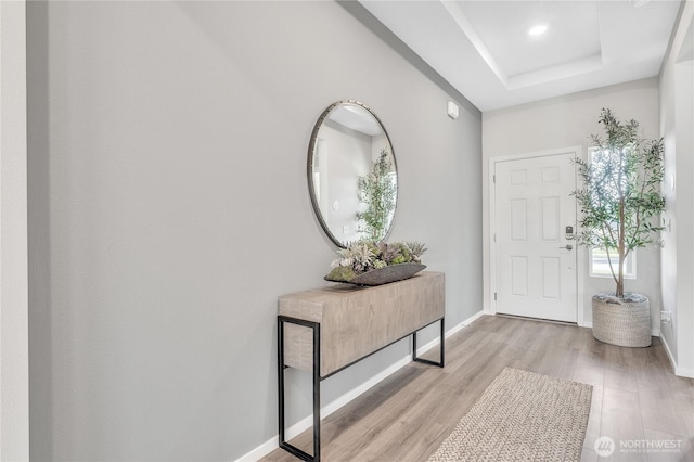 entrance foyer featuring light wood finished floors, baseboards, and a tray ceiling