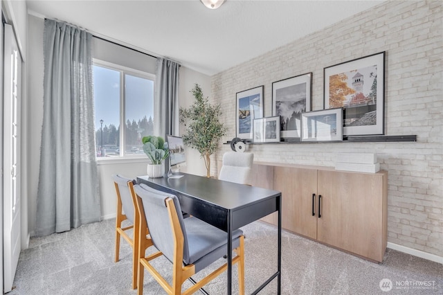 dining area featuring light carpet, brick wall, and baseboards