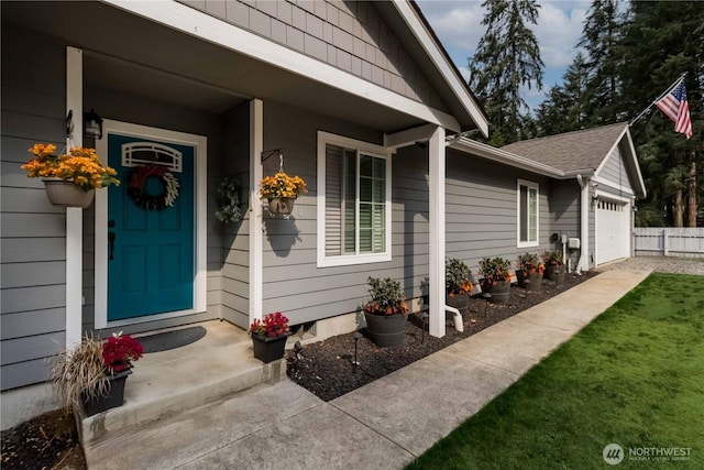 property entrance with an attached garage and a shingled roof