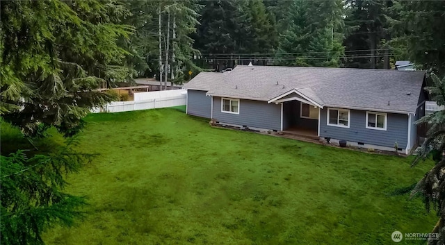 rear view of property with crawl space, a shingled roof, fence, and a lawn