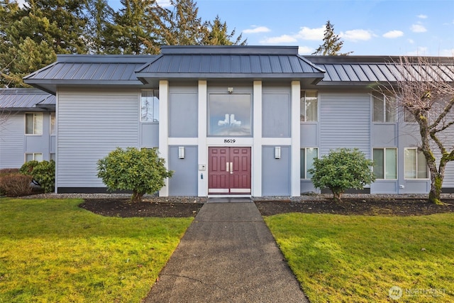 view of front of house featuring metal roof, a front lawn, and a standing seam roof