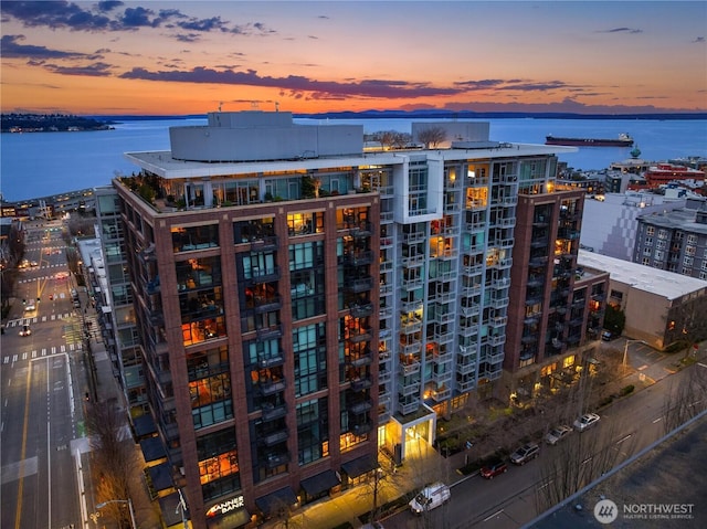 property at dusk with a water view and a city view