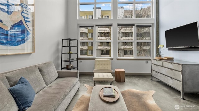 living room featuring a high ceiling, concrete floors, and baseboards