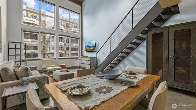 dining space with a towering ceiling and stairs