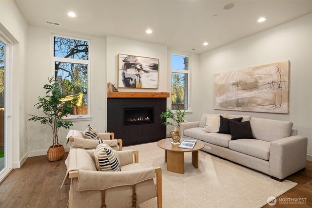 living room featuring recessed lighting, visible vents, wood finished floors, and a glass covered fireplace