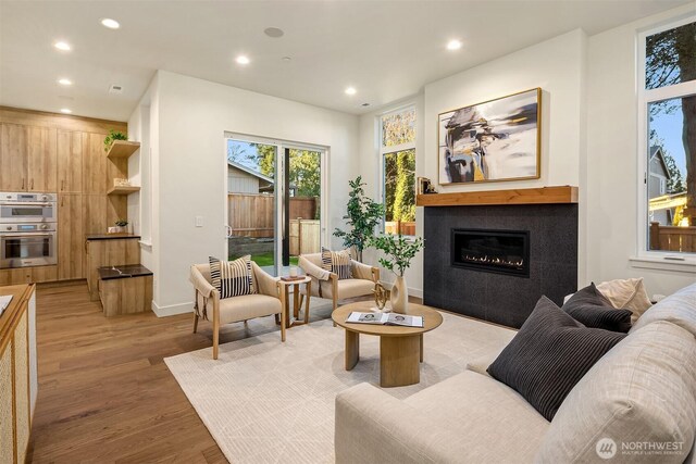 living area with recessed lighting, a fireplace, light wood-style flooring, and baseboards