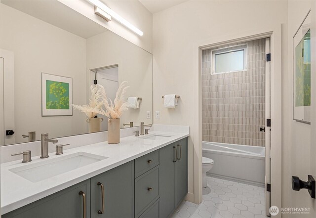 full bath featuring double vanity, a sink, toilet, and tile patterned floors