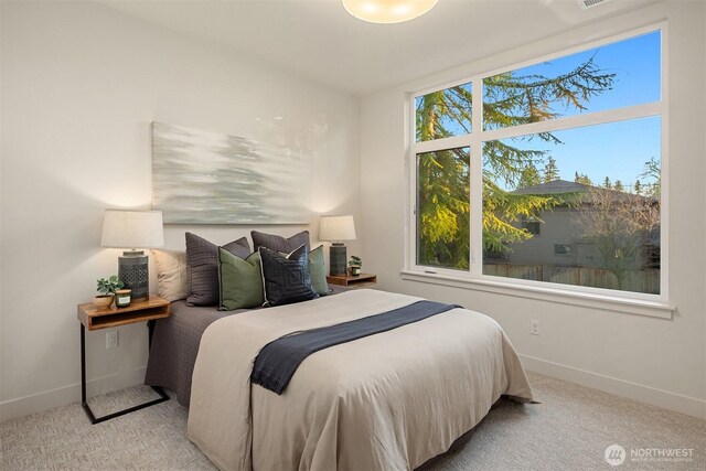 bedroom featuring multiple windows, light colored carpet, and baseboards