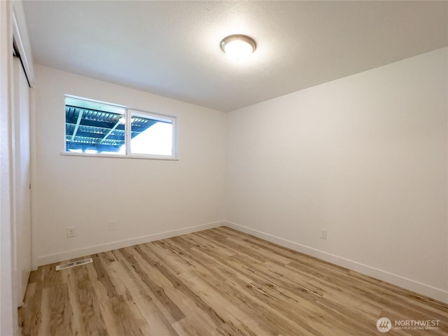 spare room featuring baseboards, visible vents, and light wood finished floors