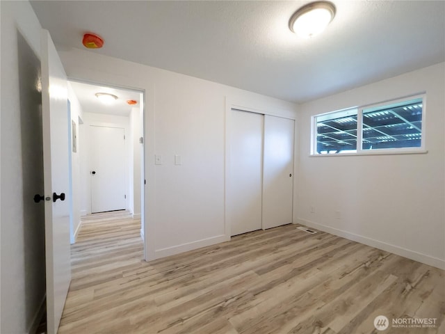 unfurnished bedroom with light wood-style floors, baseboards, and a closet