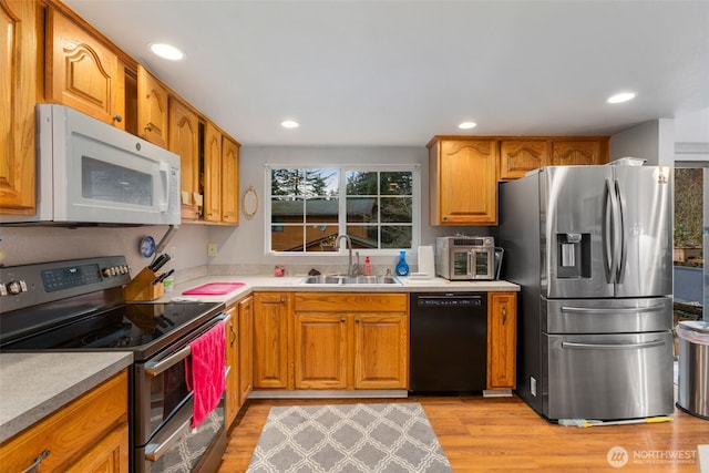 kitchen with brown cabinets, stainless steel appliances, a sink, and light countertops