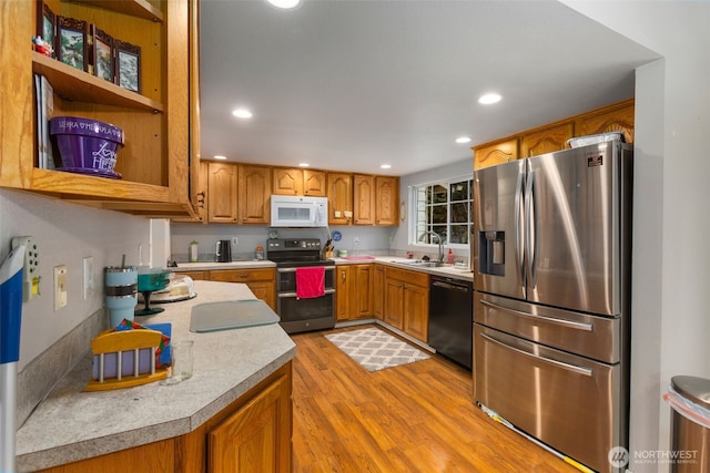 kitchen featuring brown cabinets, stainless steel appliances, light countertops, light wood-style floors, and a sink