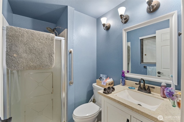 bathroom with toilet, a textured wall, a stall shower, and vanity