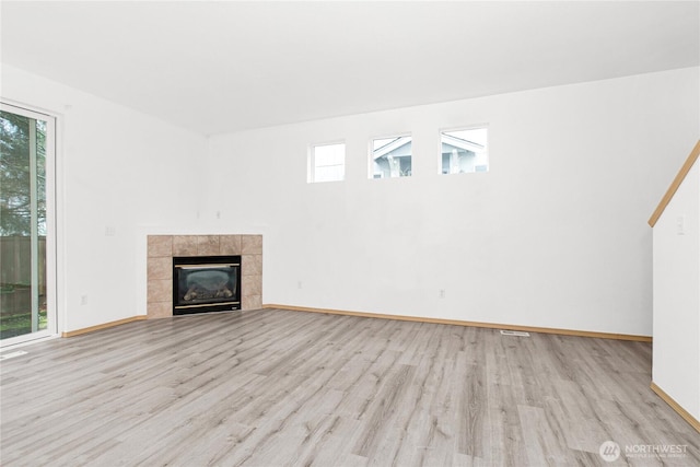 unfurnished living room featuring light wood-style floors, a fireplace, and plenty of natural light