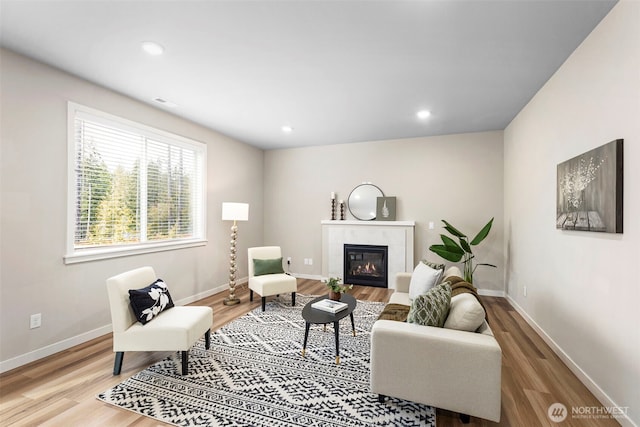 living room with a tiled fireplace, recessed lighting, light wood-type flooring, and baseboards