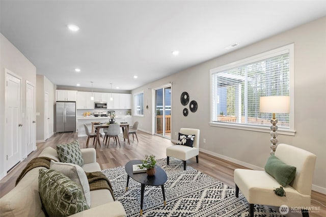 living room featuring recessed lighting, light wood-style flooring, and baseboards