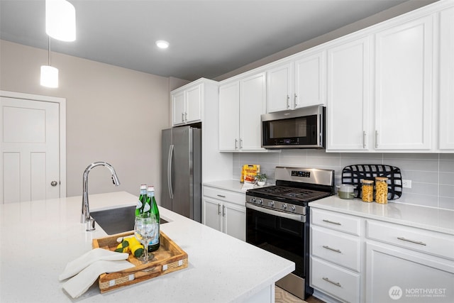 kitchen featuring a sink, white cabinetry, appliances with stainless steel finishes, tasteful backsplash, and pendant lighting