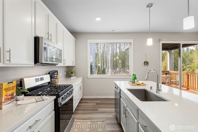 kitchen with white cabinets, pendant lighting, stainless steel appliances, and a sink