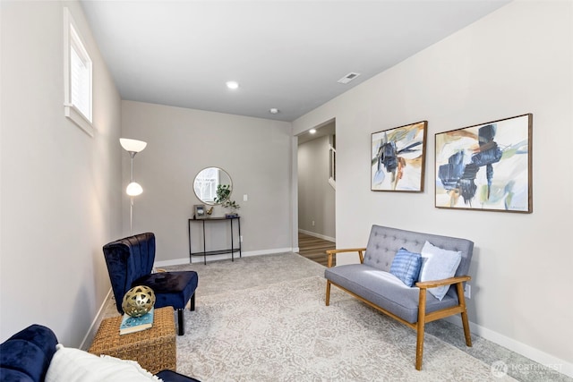 living area featuring carpet floors, visible vents, and baseboards