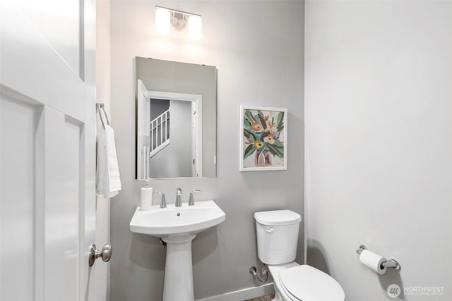 bathroom with a sink, toilet, and baseboards