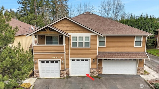 view of front of house featuring a garage, stone siding, driveway, and roof with shingles