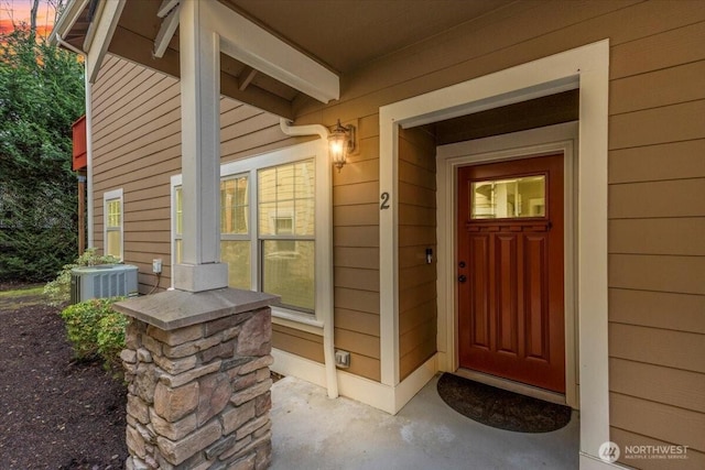 view of exterior entry with covered porch and central AC unit