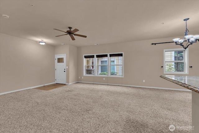 unfurnished living room with carpet, baseboards, and ceiling fan with notable chandelier