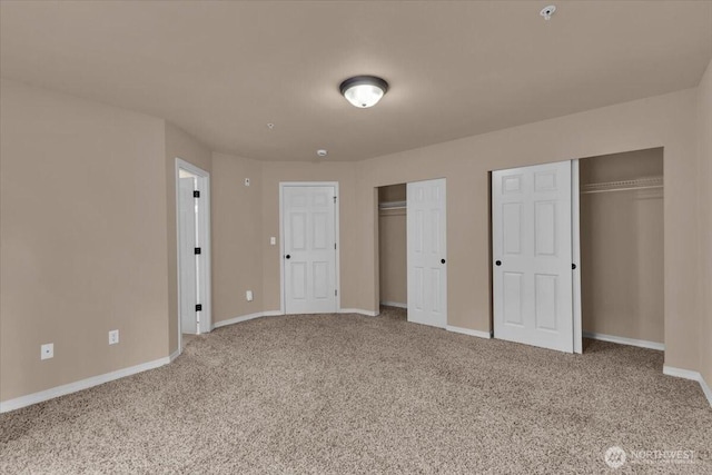 unfurnished bedroom with carpet floors, baseboards, and two closets