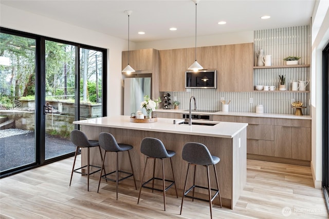 kitchen featuring a sink, hanging light fixtures, light countertops, open shelves, and modern cabinets