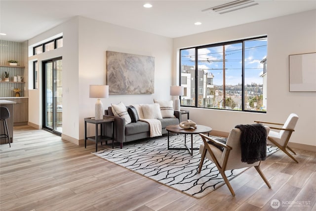 living area with recessed lighting, visible vents, light wood-style flooring, and baseboards