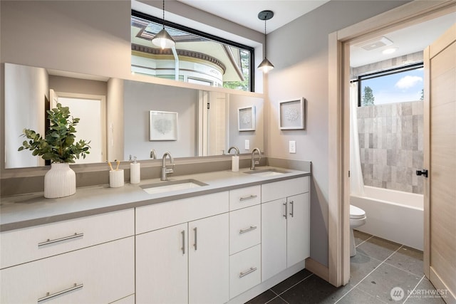 full bathroom featuring washtub / shower combination, a sink, toilet, and double vanity