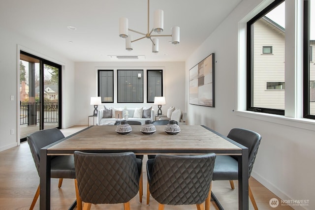 dining room with baseboards, visible vents, a notable chandelier, and light wood finished floors