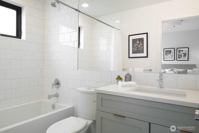 bathroom with toilet, shower / tub combo, vanity, tile walls, and tasteful backsplash