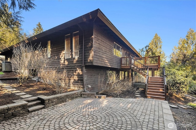 view of property exterior with central AC unit, a patio area, stairway, and a wooden deck