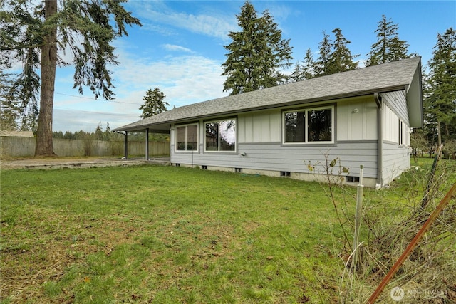 view of front of house with board and batten siding, a front yard, roof with shingles, and fence