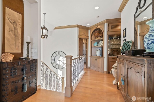 corridor featuring light wood-style flooring, crown molding, an upstairs landing, a notable chandelier, and recessed lighting