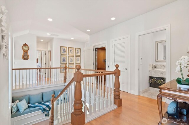 corridor with recessed lighting, an upstairs landing, and light wood-style floors