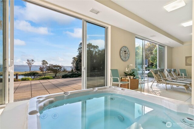 view of pool featuring a water view and an indoor hot tub