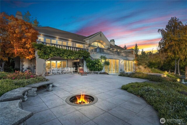 exterior space with driveway, an outdoor fire pit, a balcony, a patio area, and stucco siding