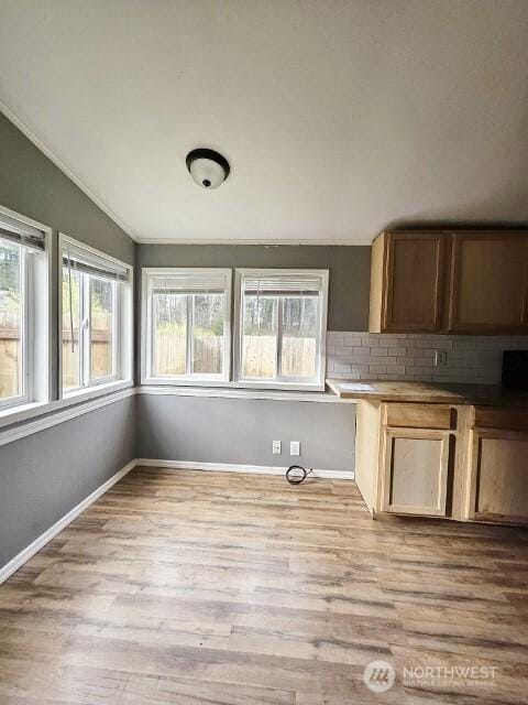 kitchen with light wood-style floors, baseboards, vaulted ceiling, and backsplash