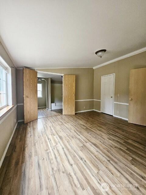 unfurnished room featuring crown molding, baseboards, and wood finished floors