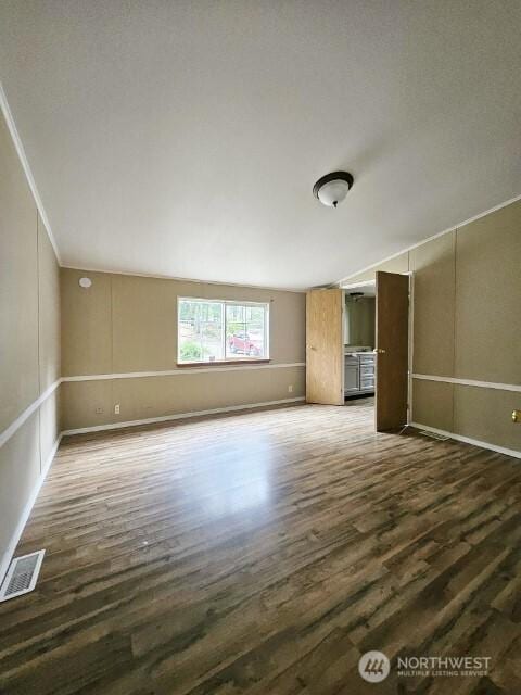 unfurnished room with visible vents and dark wood finished floors