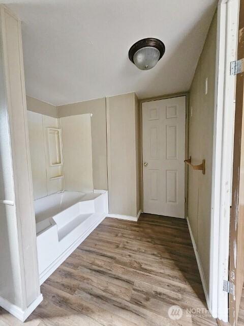 full bath featuring wood finished floors and a washtub