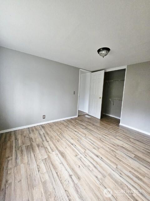 unfurnished bedroom featuring light wood-type flooring, a closet, and baseboards