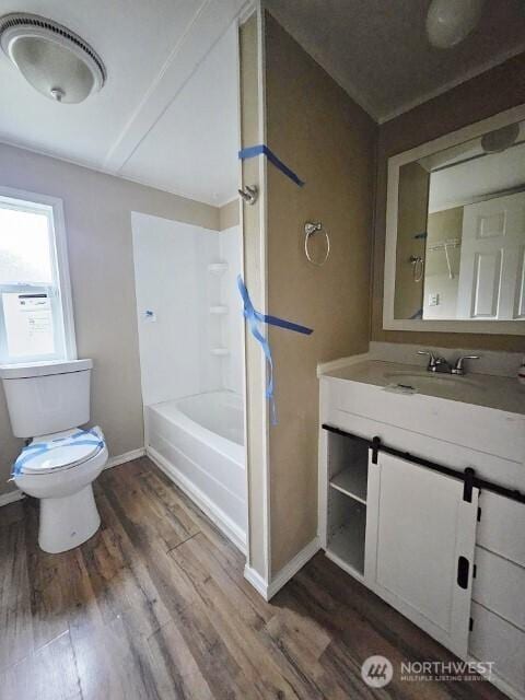 full bath featuring baseboards, toilet, wood finished floors,  shower combination, and vanity