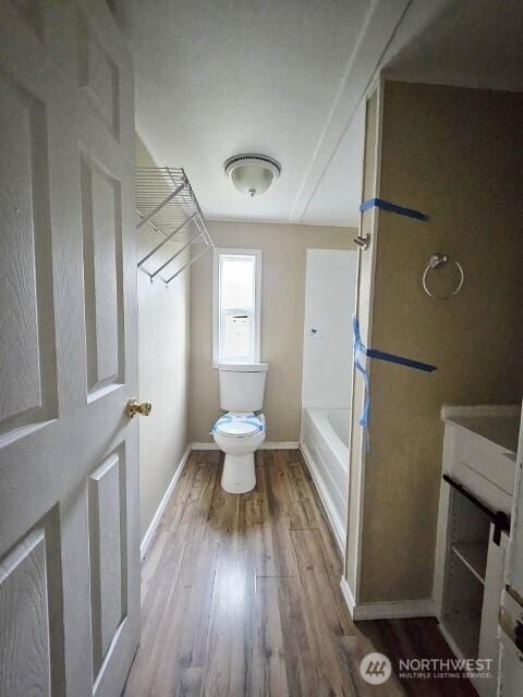 full bath with a tub, toilet, baseboards, and wood finished floors