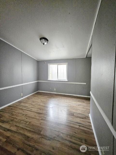 spare room with crown molding, baseboards, and wood finished floors