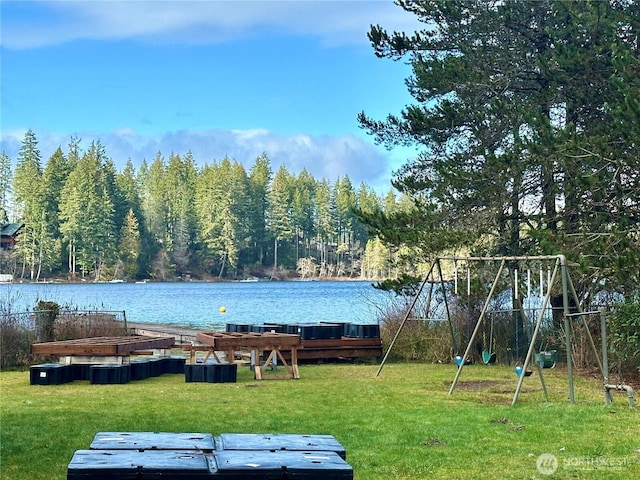 exterior space with a water view, a view of trees, and a lawn