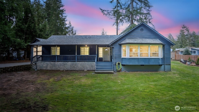 back of property at dusk with crawl space, covered porch, and a yard