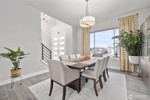 dining space featuring light wood finished floors, baseboards, stairs, and visible vents